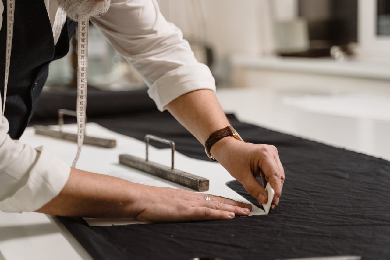 A tailor focuses on marking fabric with precision, showcasing craftsmanship.